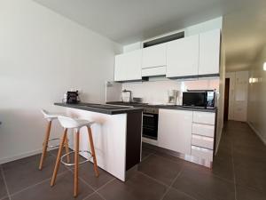 eine Küche mit weißen Schränken und Barhockern in der Unterkunft APPARTEMENT TERRASSE VUE MER Sea view terrace apartment "Etoile de Mer" in Menton