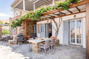 a patio with a table and chairs under a pergola at Oikia Petra in Agios Ioannis