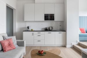 eine Küche mit weißen Schränken und einem Tisch im Wohnzimmer in der Unterkunft Sanhaus Apartments - Apartament Playa 1 z widokiem na morze in Sopot