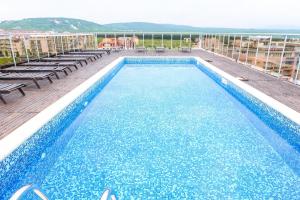a swimming pool on top of a building with chairs at North Beach Hotel in Primorsko