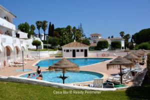 ein Pool mit Sonnenschirmen und Menschen in einem Resort in der Unterkunft Casa Blu, Beach Boho Chic, Beach and Pool - Fast Wifi in Porches