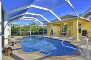 een zwembad met een patio en een huis bij Villa Valmora in Cape Coral