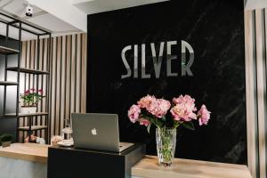 un vase de fleurs roses sur un bureau avec un ordinateur portable dans l'établissement Готельно-рестораний комплекс Silver, à Ivano-Frankivsk