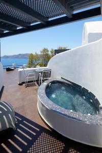 un patio con tavolo e ampia vasca da bagno. di Oia Suites a Oia