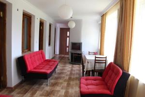 a living room with two red chairs and a table at Guest house Racha in Ambrolauri
