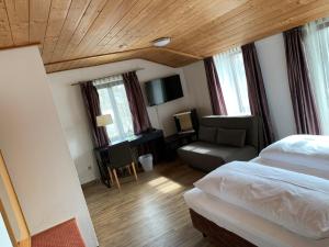 een slaapkamer met een bed, een stoel en een bank bij Hotel Seeluna am Klostersee in Ebersberg