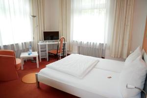 Schlafzimmer mit einem Bett und einem Schreibtisch mit einem Computer in der Unterkunft Wohlfühlhotel Saxonia in Bad Kissingen