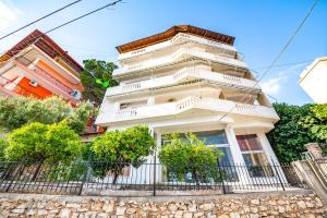 un edificio bianco con una recinzione di fronte di Ideal ApartHotel Saranda a Sarandë