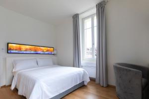 a white bedroom with a bed and a window at Lac Hotel in Melide