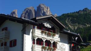 un edificio con flores en él con una montaña en Villa Kofler Wonderland Resort en Campitello di Fassa