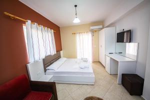 Piccola camera con letto bianco e scrivania. di Ideal ApartHotel Saranda a Sarandë
