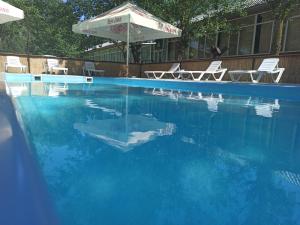 ein Becken mit blauem Wasser, Stühlen und einem Sonnenschirm in der Unterkunft Holiday Park Dunay in Kislitsa