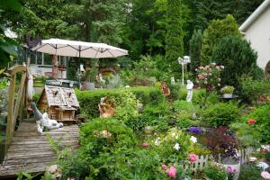 a garden with a wooden deck with flowers and an umbrella at Wohlfühlhotel Saxonia in Bad Kissingen
