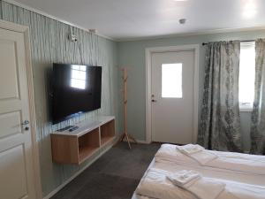 a hotel room with two beds and a flat screen tv at Bech's Hotell & Camping in Mo i Rana