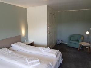 a hotel room with two beds and a blue chair at Bech's Hotell & Camping in Mo i Rana