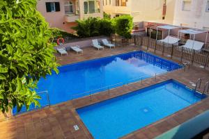 una gran piscina azul con sillas y un edificio en Apartamentos Royal Life, en Mahón