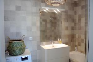 een badkamer met een wastafel, een spiegel en een bad bij Arbre Blanc, une folie montpelliéraine in Montpellier