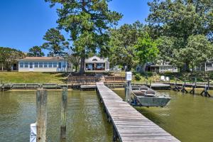 a dock with a boat on the water with a house at Riverfront Cottage Fire Pit and Kayaks in Deltaville