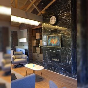 a living room with a fireplace and a clock on a wall at Kaya Life Resort in Uzungöl
