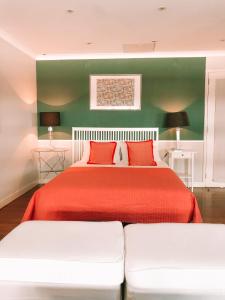 a bedroom with a large bed with red sheets and green walls at 7Rios Rooms in Lisbon