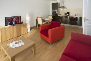 a living room with a red chair and a tv at Domitys Les Cigales du Lubéron in Cavaillon