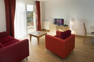 a living room with two red chairs and a television at Domitys Les Cigales du Lubéron in Cavaillon