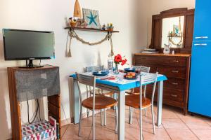 een keuken met een blauwe tafel met stoelen en een tv bij Casetta Sarina in Milazzo