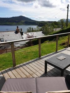 a wooden deck with a table and a bench on it at Rockview in Portree
