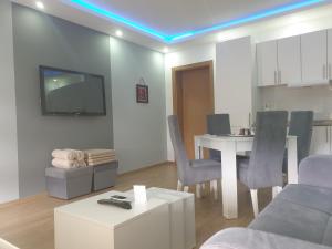 un soggiorno con tavolo, sedie e TV di Apartmani Kruna a Vrdnik