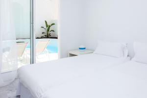 a white bedroom with a bed and a balcony at Villa 34 in Corralejo
