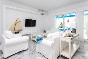 a living room with white furniture and a small boat on the wall at Villa 34 in Corralejo