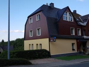 een groot rood en geel huis aan een straat bij Ferienwohnung mit Garten und Spielplatz in Klingenthal