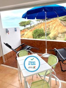 a table and chairs with an umbrella on a balcony at Forte Apartment in Albufeira