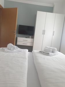 1 dormitorio con 2 camas con sábanas blancas y TV en Apartmani Kruna en Vrdnik