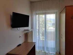 Habitación con ventana y TV de pantalla plana en la pared. en Garni Maria, en Varna