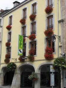 a yellow building with flower boxes on its windows at Hotel Cheval De Bronze in Remiremont