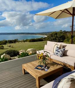 a patio with a couch and an umbrella and a table at The Cape in Emu Bay