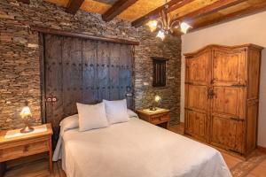 a bedroom with a bed and a stone wall at Alojamientos Rurales Los Macabes in Alpujarra de la Sierra