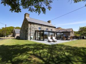 an exterior view of a stone house with large windows at Garth Morthin The Farmhouse in Porthmadog