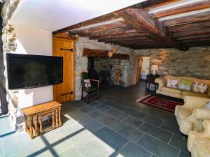 a living room with a tv and a couch at Garth Morthin The Farmhouse in Porthmadog
