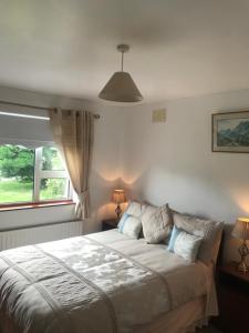 a bedroom with a bed with two lamps and a window at Marguerite's B&B in Glenties