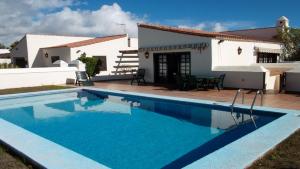 a villa with a swimming pool in front of a house at Exclusively located Golf Villa with heated pool in San Miguel de Abona