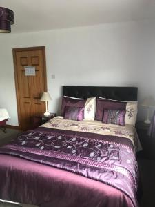 a bedroom with a large bed with a purple comforter at Marguerite's B&B in Glenties