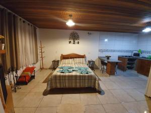 a bedroom with a bed and a table and a kitchen at Chalé Sonho Meu in Monte Verde