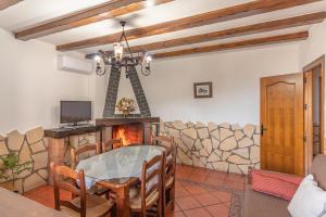 uma sala de jantar com uma mesa de vidro e uma lareira em Alojamientos Rurales Los Macabes em Alpujarra De La Sierra