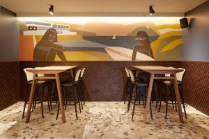 a restaurant with two tables and a mural at Hotel SANSEbay in Donostia-San Sebastián