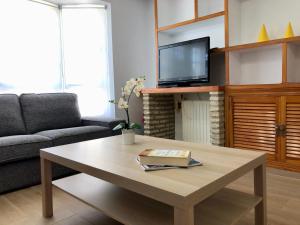 sala de estar con mesa de centro y TV en Barrosa Playa 5, en Chiclana de la Frontera