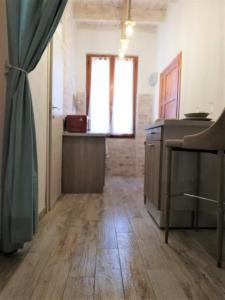a room with a kitchen with wooden floors and a window at Alghero Old Town Apartment in Alghero