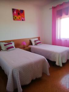 Roncão的住宿－Vivenda Palheiras，客房设有2张带白色床单的床和窗户。