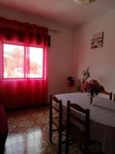 a room with a table and a window with red curtains at Vivenda Palheiras in Roncão